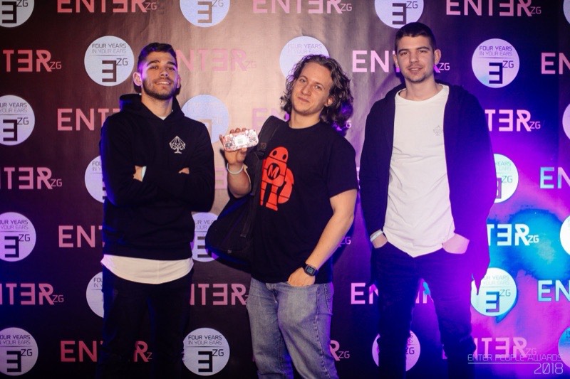 Albert Gajšak holding a small award on a step-and-repeat backdrop with two other people at the ENTER Zagreb awards.