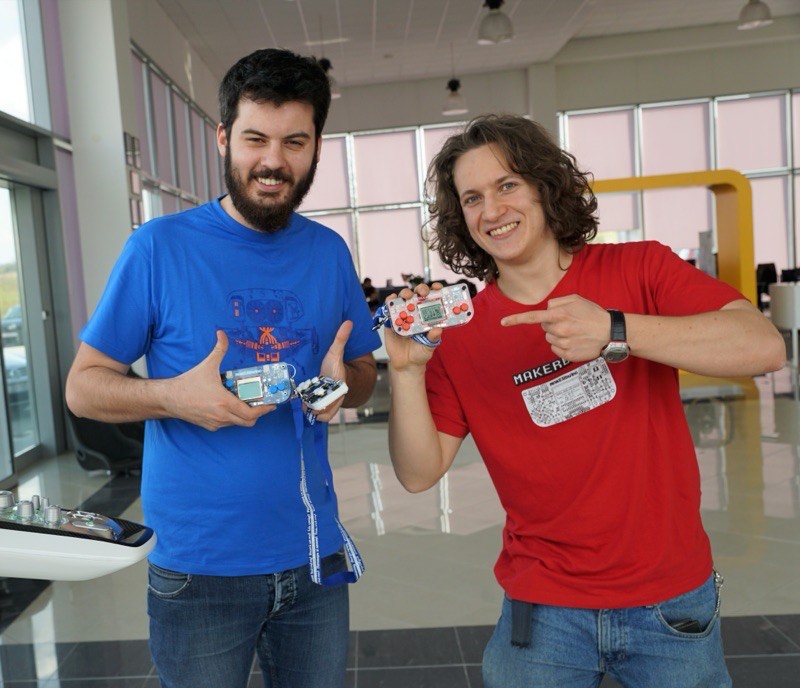 Albert Gajšak and a colleague each holding up a CircuitMess console and pointing at it.